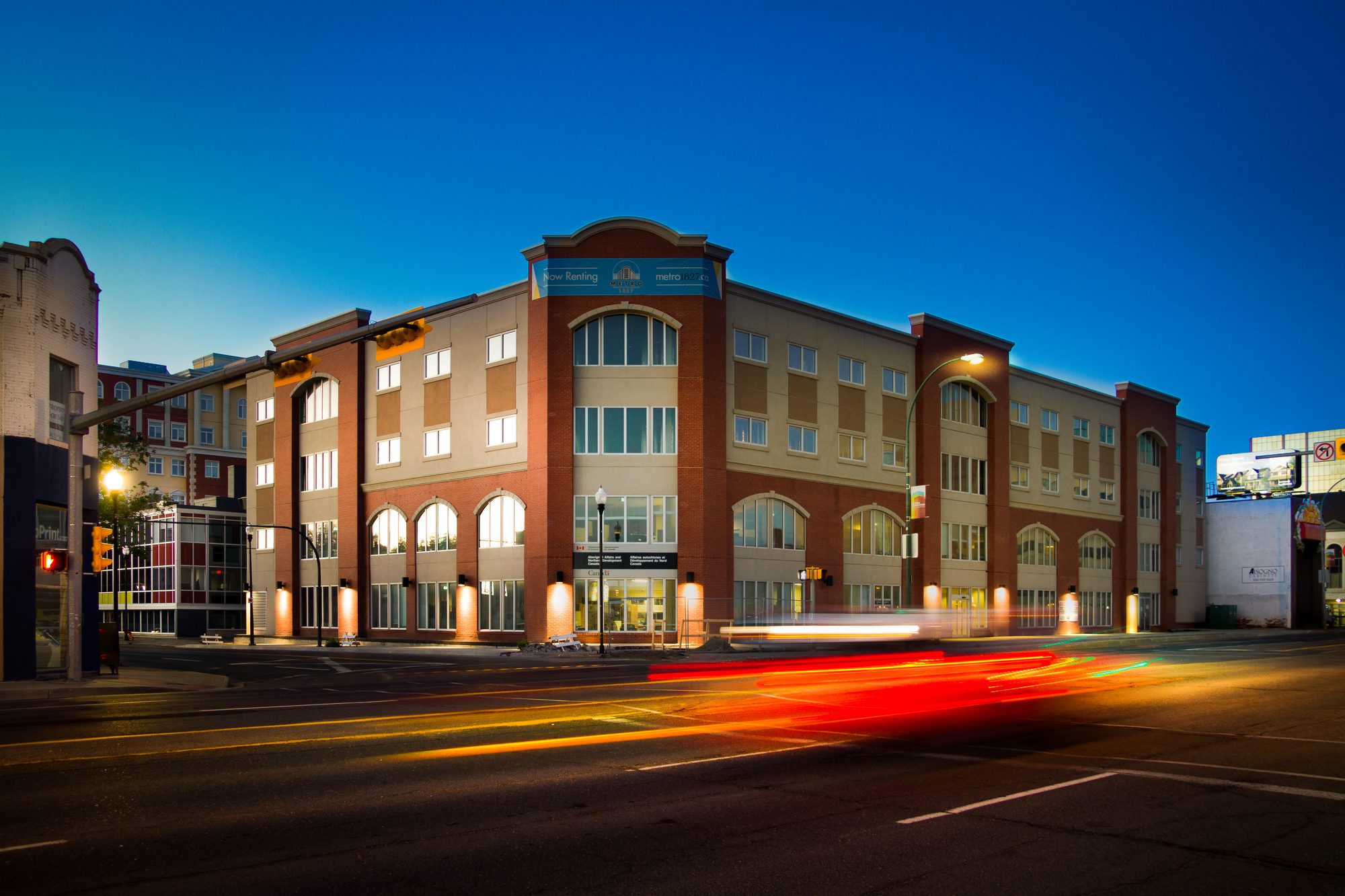 The Metro 1827 apartment building at dusk, with traffic passing on Albert Street in downtown Regina