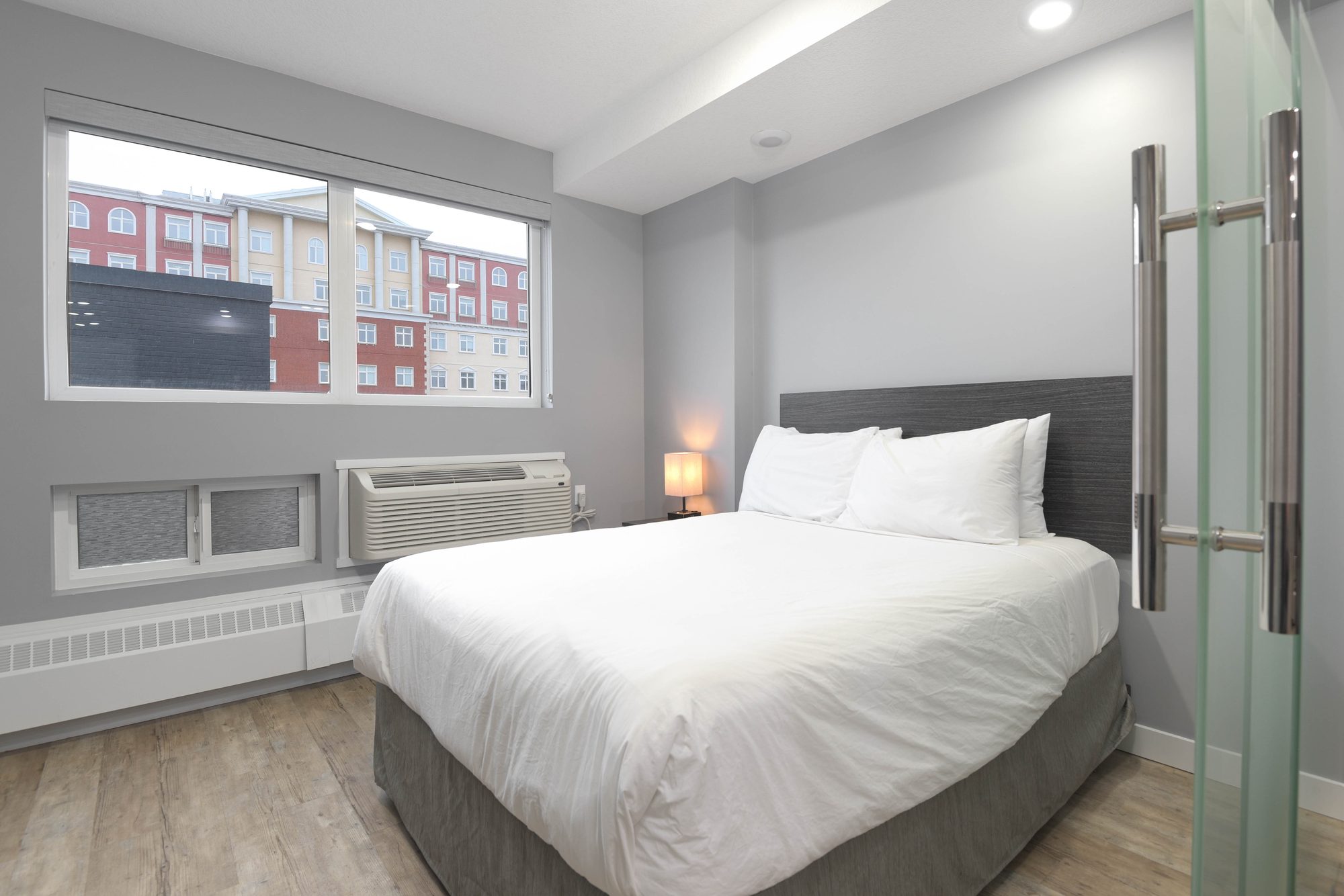 Living room with grey sofa, artwork, and frosted glass bedroom partition