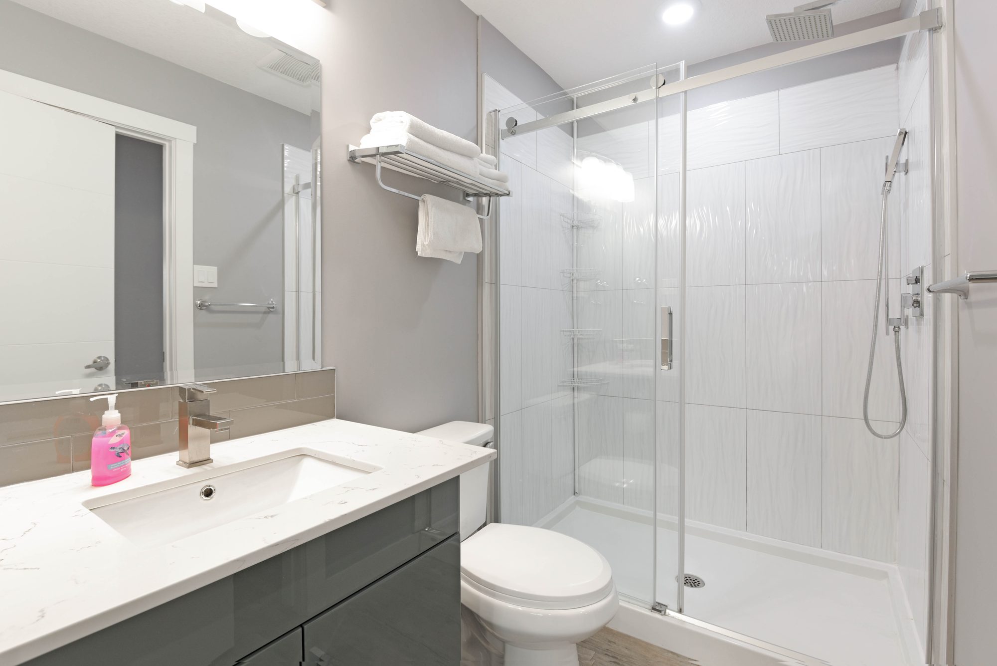 Bathroom with quartz vanity, toilet, and glass walk-in shower