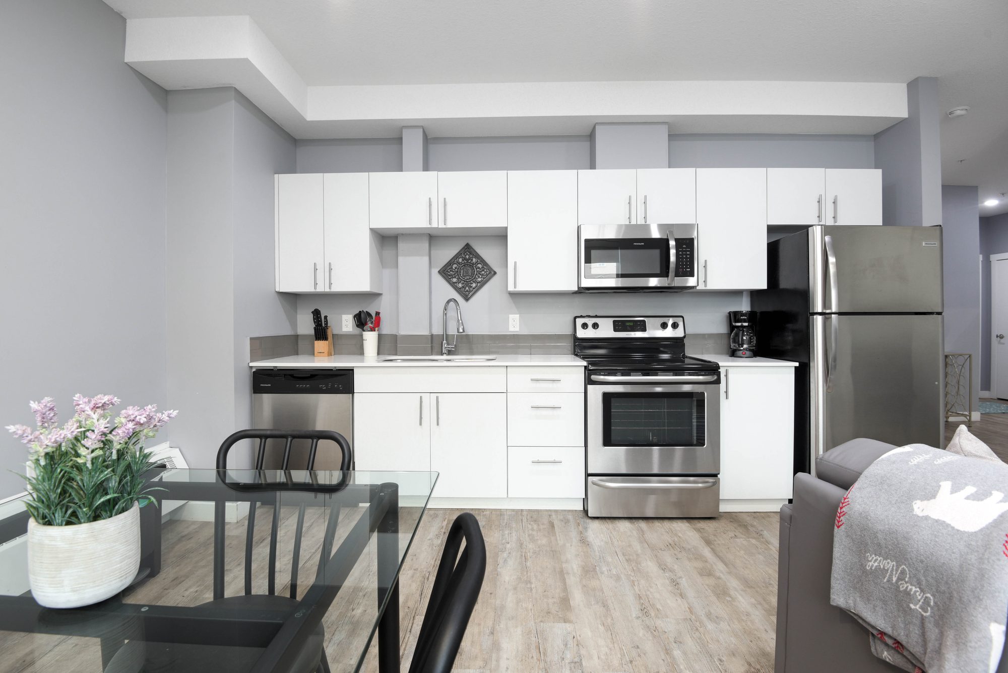 Two bedroom kitchen with white cabinets, stainless steel appliances, and dining seating