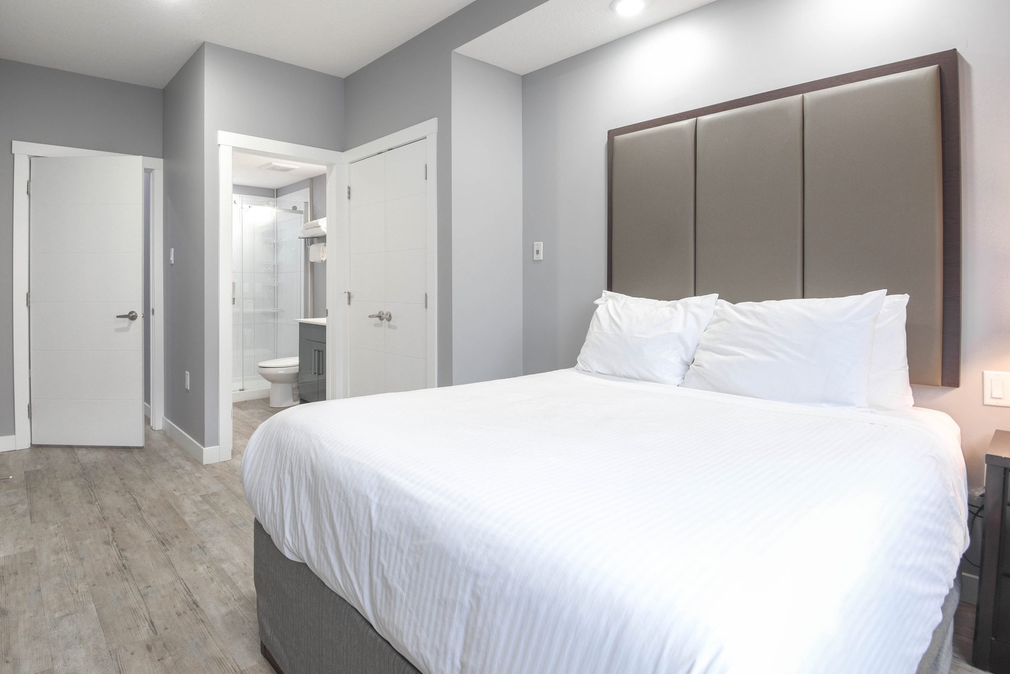 Bedroom with tall upholstered headboard and en suite bathroom door